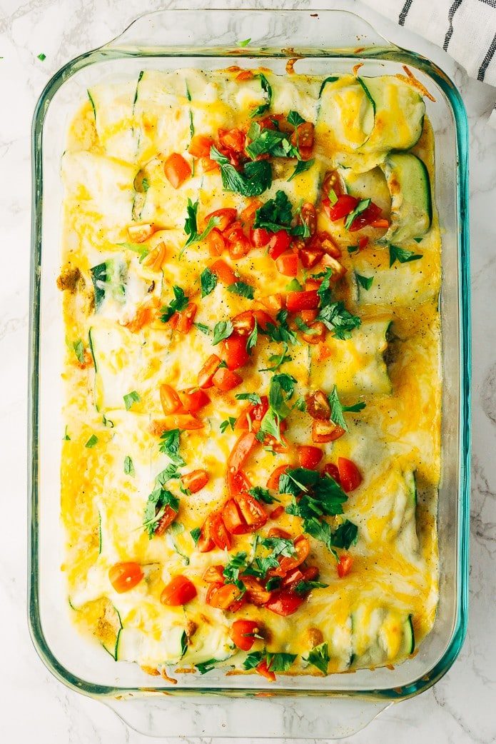 green chile chicken enchiladas topped with tomatoes