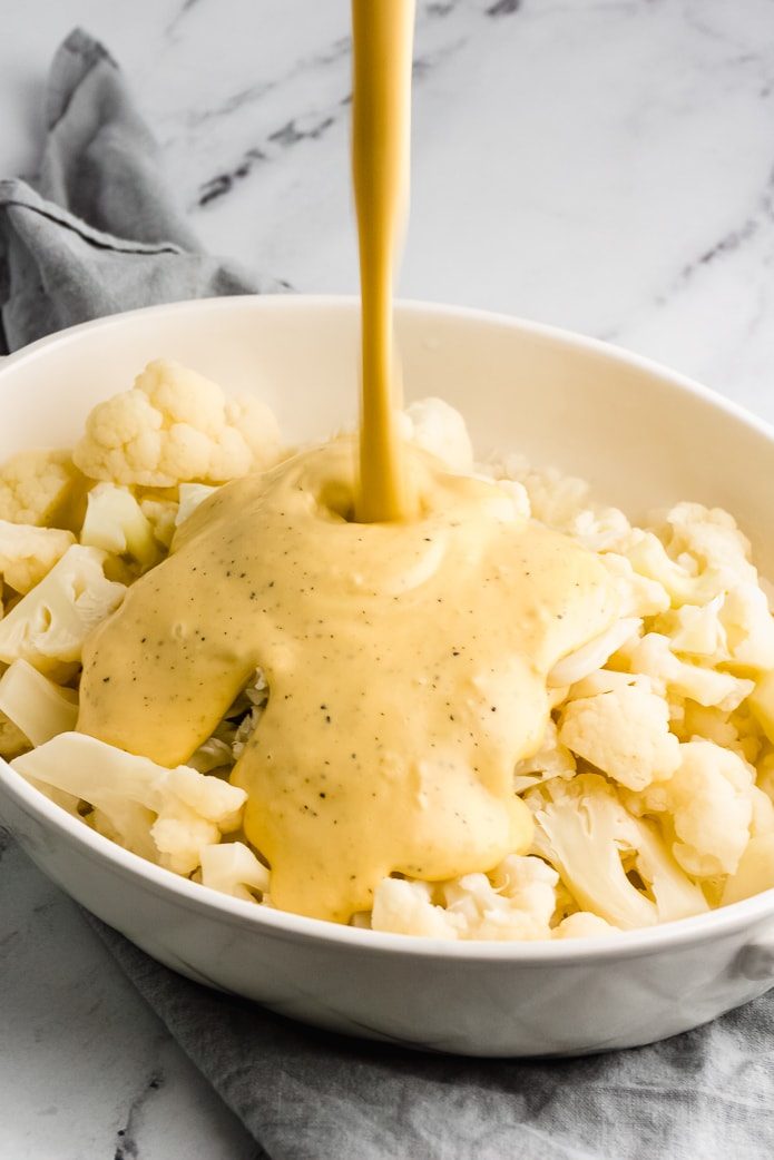 cheese sauce poured on cauliflower for keto mac and cheese