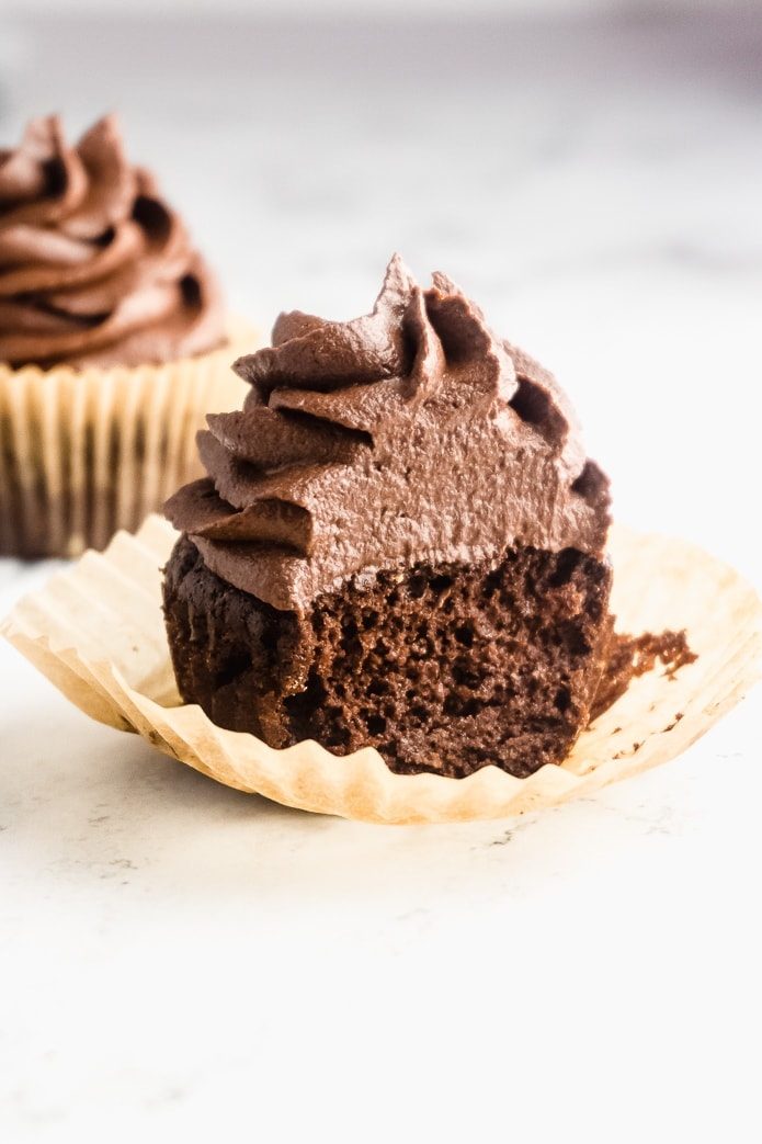 moist keto cupcake with chocolate buttercream icing and a bit taken out of it