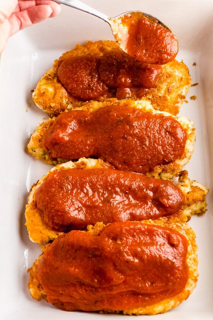 topping keto breaded chicken with low-carb tomato sauce